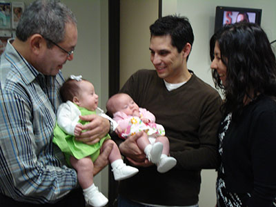 Dr. Diaz holding Frozen Egg Baby #49 Baby Grace while the proud parents hold her twin sister Julia, Frozen Egg baby #50.